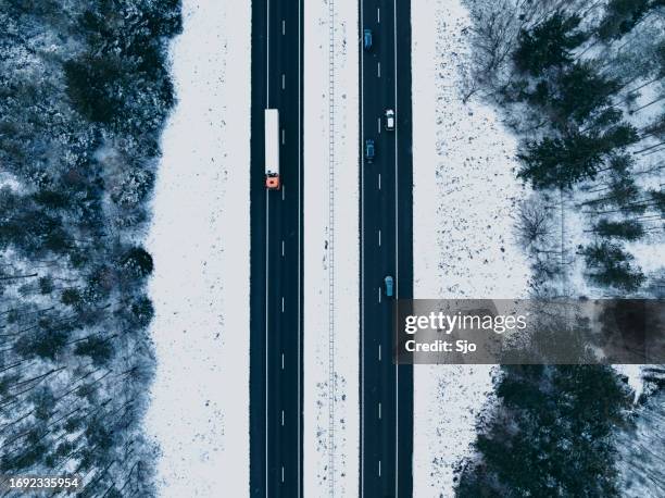 highway through a snowy forest landscape seen from above - car underside stock pictures, royalty-free photos & images
