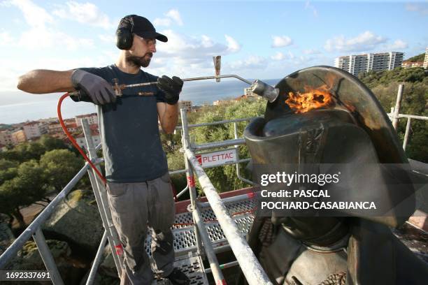 Restorer uses a blowtorch to heat the bronze statue of Napoleon Bonaparte before applying a protective layer in Ajaccio on the French Mediterranean...