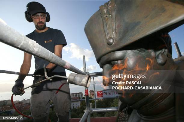 Restorer uses a blowtorch to heat the bronze statue of Napoleon Bonaparte before applying a protective layer in Ajaccio on the French Mediterranean...