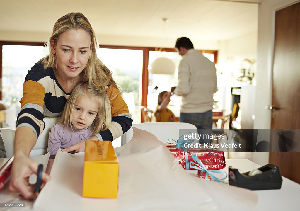 Mother helping daughter with wrapping up present