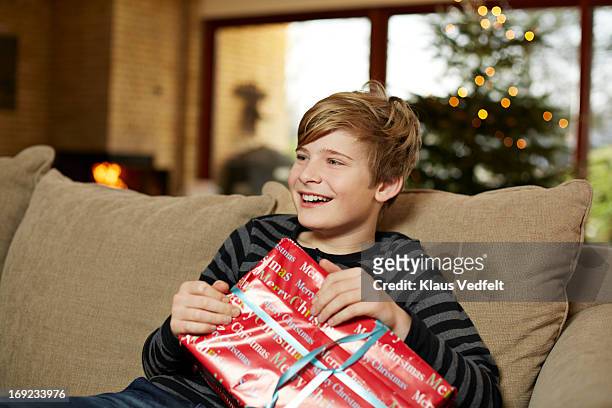 Boy laughing in sofa holding present