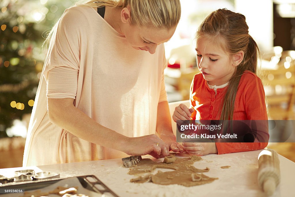 Mother helping daughter with christmas cookies