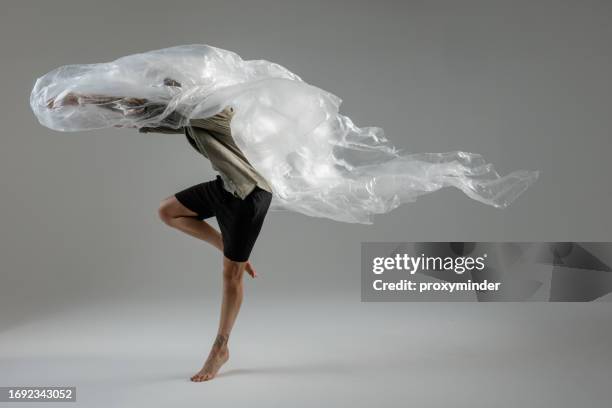 modern male dancer on gray background playing with tin polyethylene - plastic folie stockfoto's en -beelden