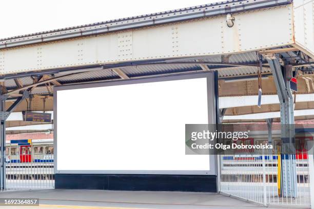 an empty billboard against a train on a railway station - london billboard stock pictures, royalty-free photos & images