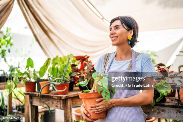 mujer adulta media mirando hacia otro lado contemplando el jardín - mercado de flores fotografías e imágenes de stock