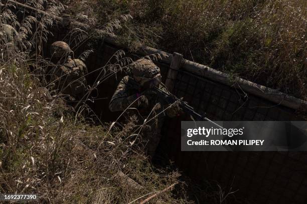 Ukrainian members of the OPFOR battalion move in a trench as they take part in a military training in the Donetsk region on September 26 amid the...