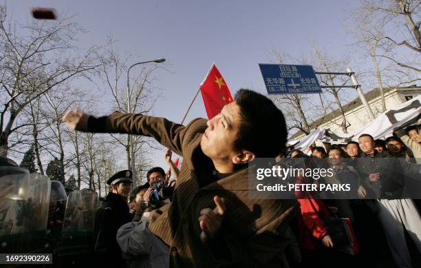 Demonstrator throws a full can of drink at the Japanese embassy in Beijing as thousands gather outside to protest Japan's handling of its wartime...