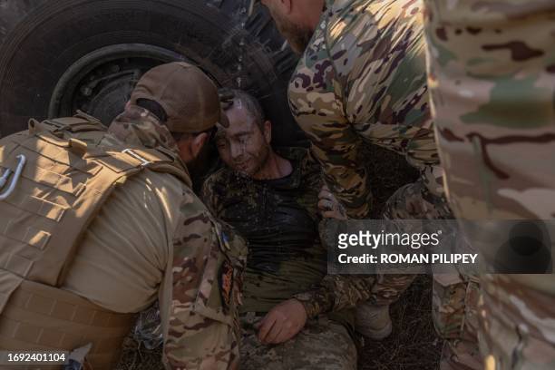 Ukrainian members of the OPFOR battalion pour water on a serviceman feeling faint during a military training in the Donetsk region on September 26...