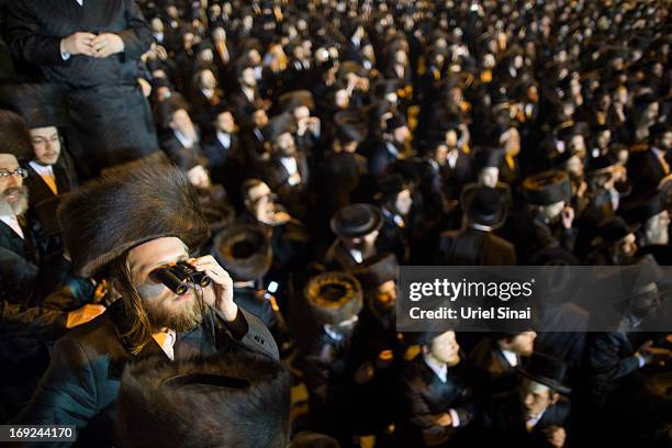 Man looks through binoculars as tens of thousands of Ultra-Orthodox Jews attend the wedding of Rabbi Shalom Rokeach, the grandson of the leader of...