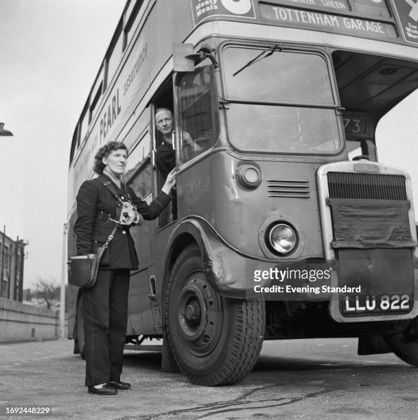 Bus conductress stands beside a Routemaster bus and its driver, London, May 2nd, 1958. A bus strike was to be held from May 5th until June 20th.