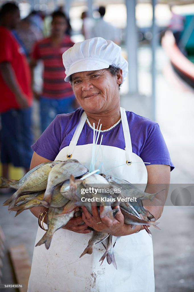 Fishworker holding big stack of fish at market