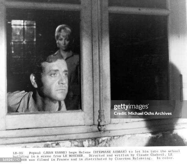 Jean Yanne looks out a window next to Stephane Audran in a scene from the film 'Le Boucher', 1970.