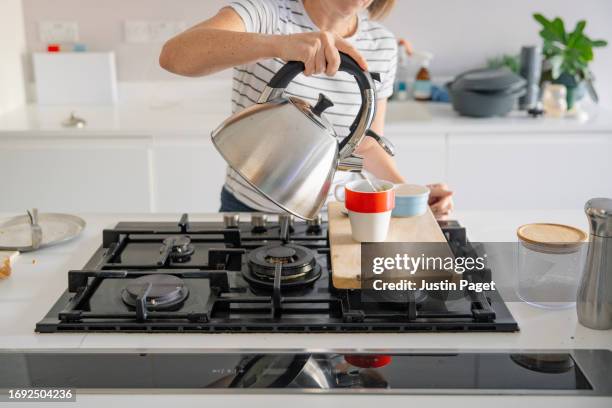 making a cup of tea - an unrecognisable woman pours boiling water into a mug - kettle stock pictures, royalty-free photos & images