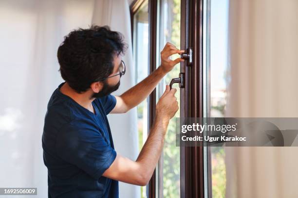 man is taking precautions against burglary - open window frame stock pictures, royalty-free photos & images