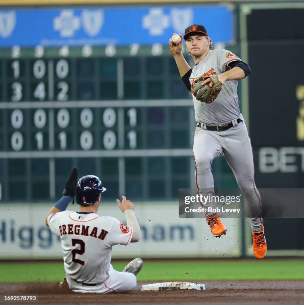 Gunnar Henderson of the Baltimore Orioles throws to first base to complete a double play as Alex Bregman of the Houston Astros slides in the second...