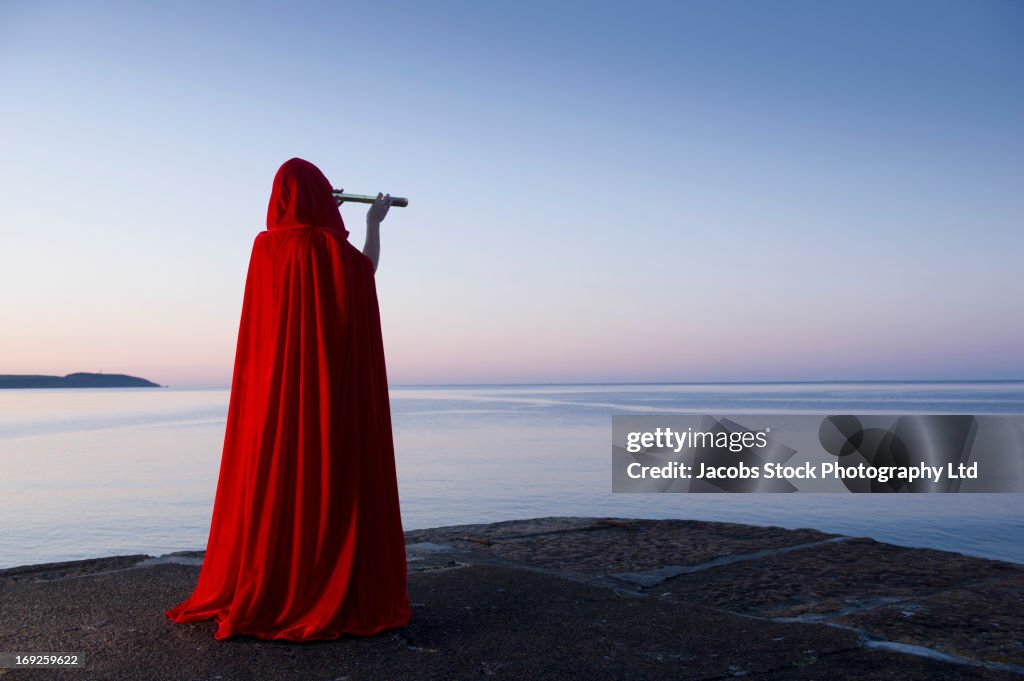 Caucasian woman with telescope overlooking ocean