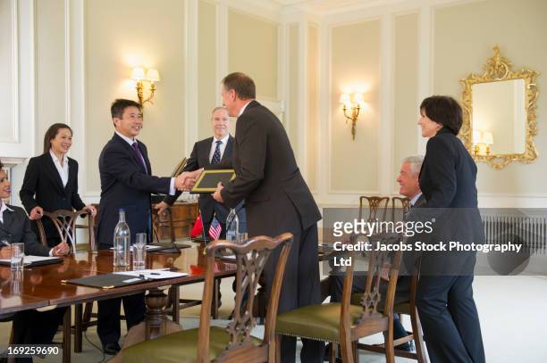 business people trading plaques in meeting - politician meeting stock pictures, royalty-free photos & images