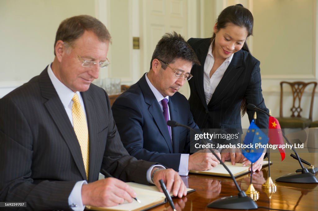 Businessmen signing books in meeting