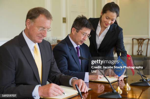 businessmen signing books in meeting - ambassador stock pictures, royalty-free photos & images