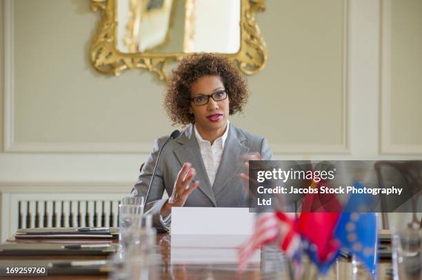 mixed race businesswoman talking in microphone - diplomati stock pictures, royalty-free photos & images