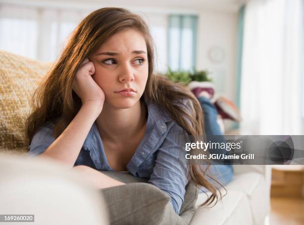anxious hispanic girl laying on sofa - malumore foto e immagini stock