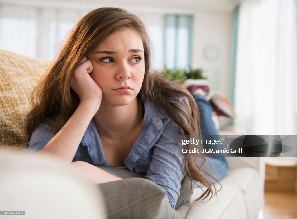 Anxious Hispanic girl laying on sofa