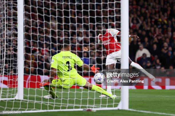 Bukayo Saka of Arsenal scores the team's first goal past Walter Benitez of PSV Eindhoven during the UEFA Champions League match between Arsenal FC...