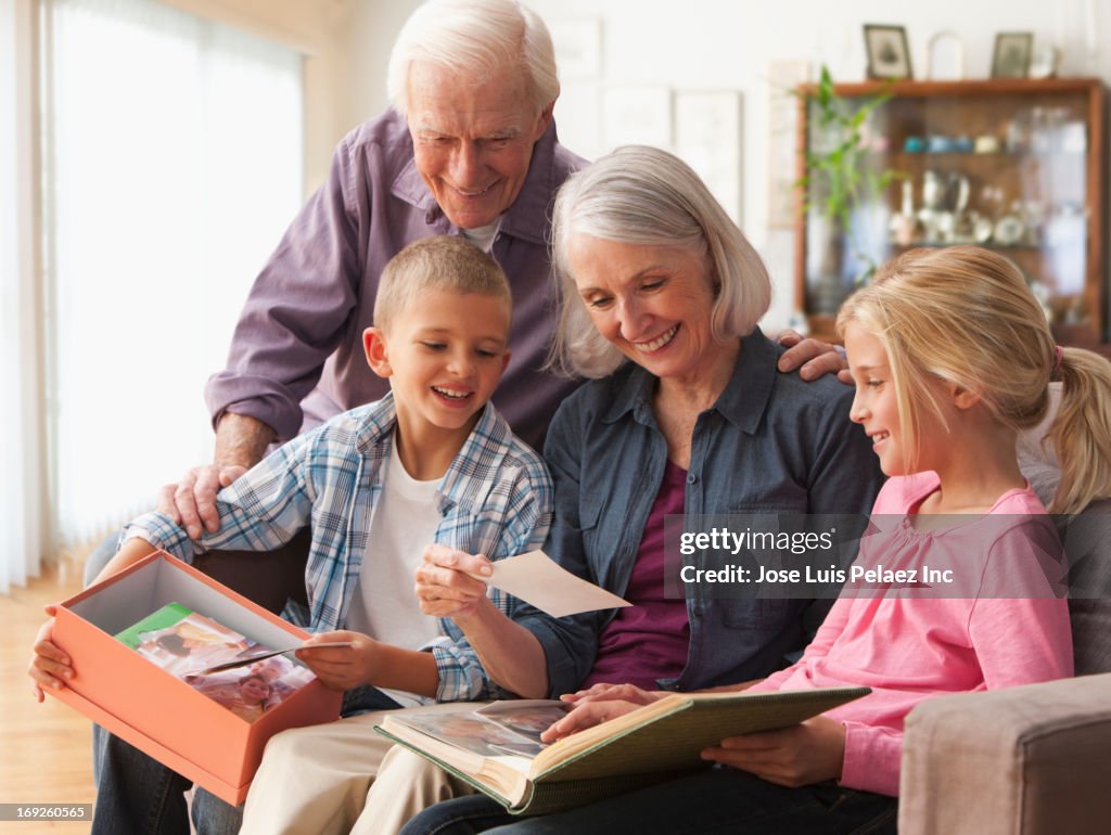 Caucasian couple looking at photographs with grandchildren