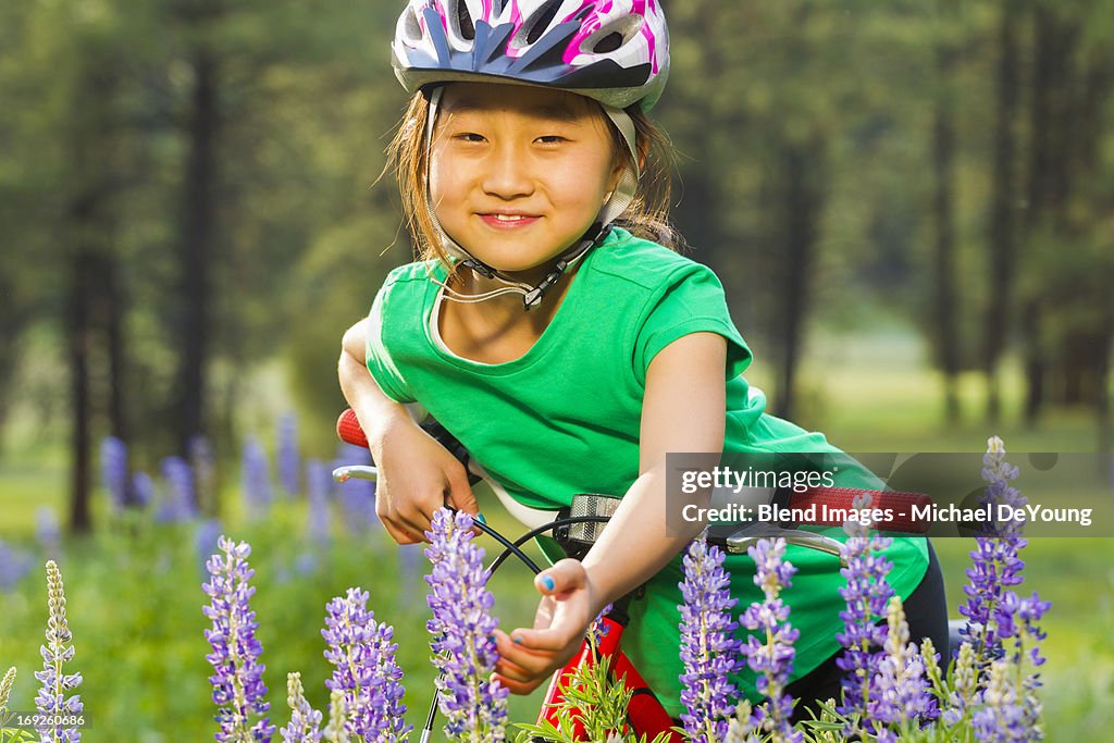 Asian girl sitting on bicycle in meadow