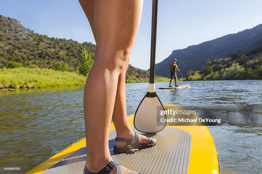 Hispanic woman riding paddle board