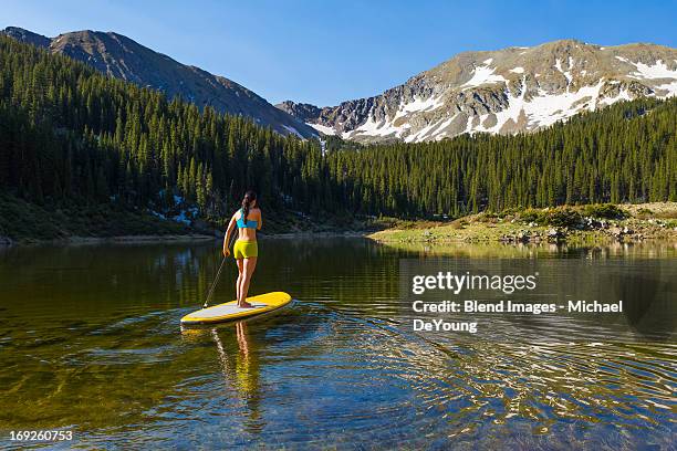 hispanic woman riding paddle board - taos stock-fotos und bilder