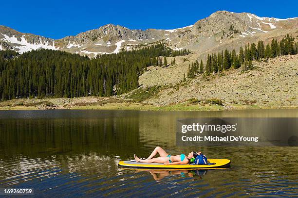 hispanic woman laying on paddle board - barefoot snow stock pictures, royalty-free photos & images
