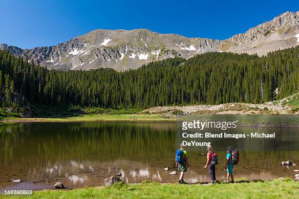 hikers admiring still lake in rural landscape - taos fotografías e imágenes de stock