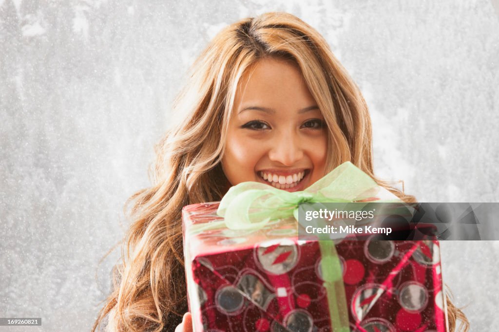 Mixed race woman holding present in snow