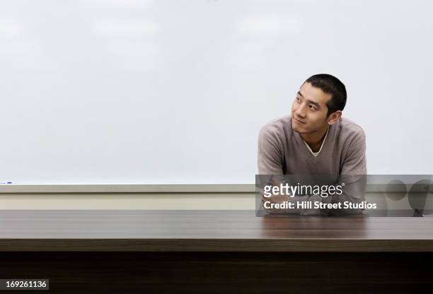 chinese student standing at whiteboard in classroom - leaning stock-fotos und bilder