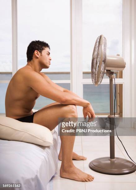 hispanic man sitting in front of fan - man mid 20s warm stock pictures, royalty-free photos & images