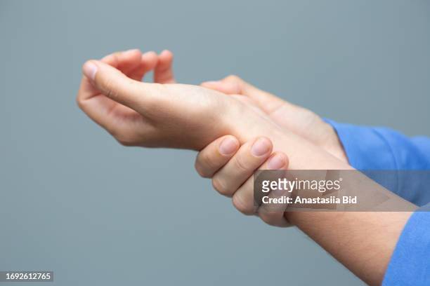 woman holding her injured wrist by her hand.closeup photography with copy space. - karpaltunnelsyndrom bildbanksfoton och bilder