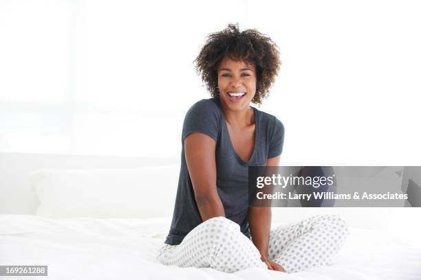 black woman sitting on bed - bed on white background stock-fotos und bilder