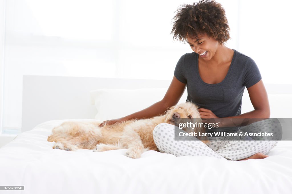 Black woman petting dog on bed