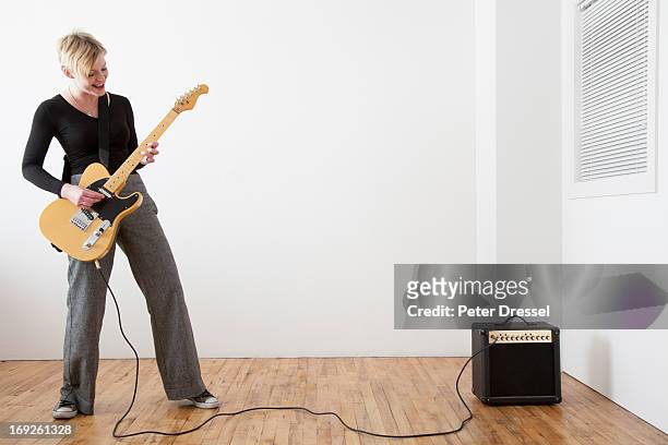caucasian woman playing electric guitar - guitar amp stock-fotos und bilder