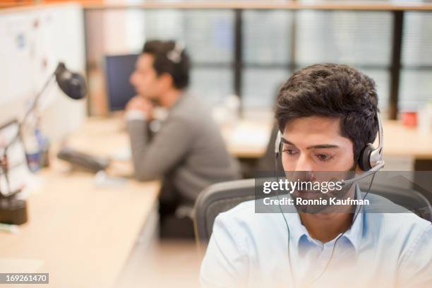 indian businessman wearing headset at desk - terceirização - fotografias e filmes do acervo