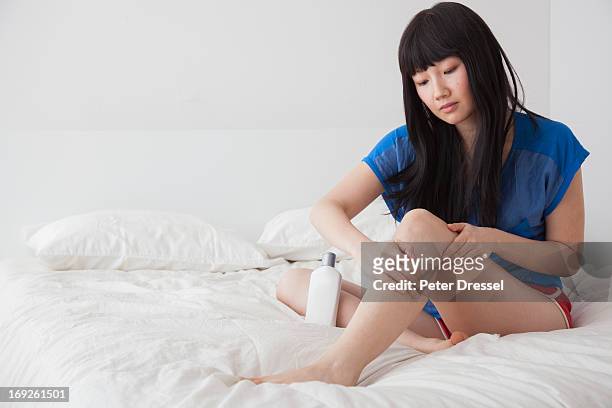 chinese woman moisturizing legs on bed - beautiful asian legs stockfoto's en -beelden