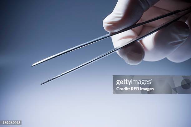 close up of hispanic doctor holding tweezers - pince chirurgicale photos et images de collection