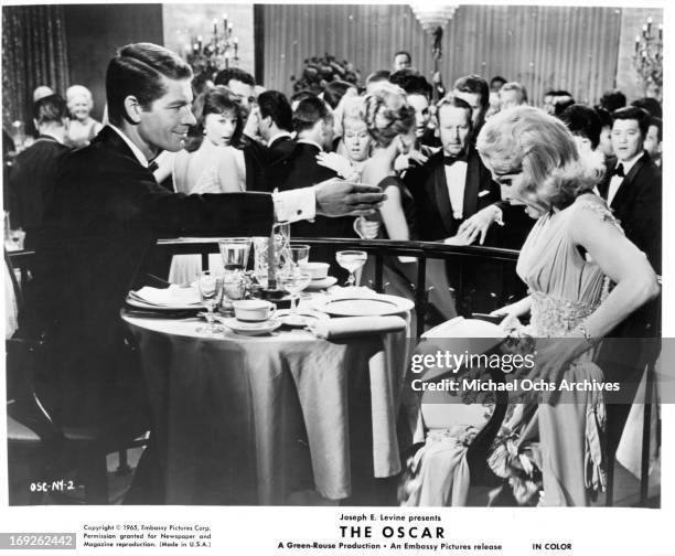 Stephen Boyd tosses a plate into a woman's lap in a scene from the film 'The Oscar', 1966.