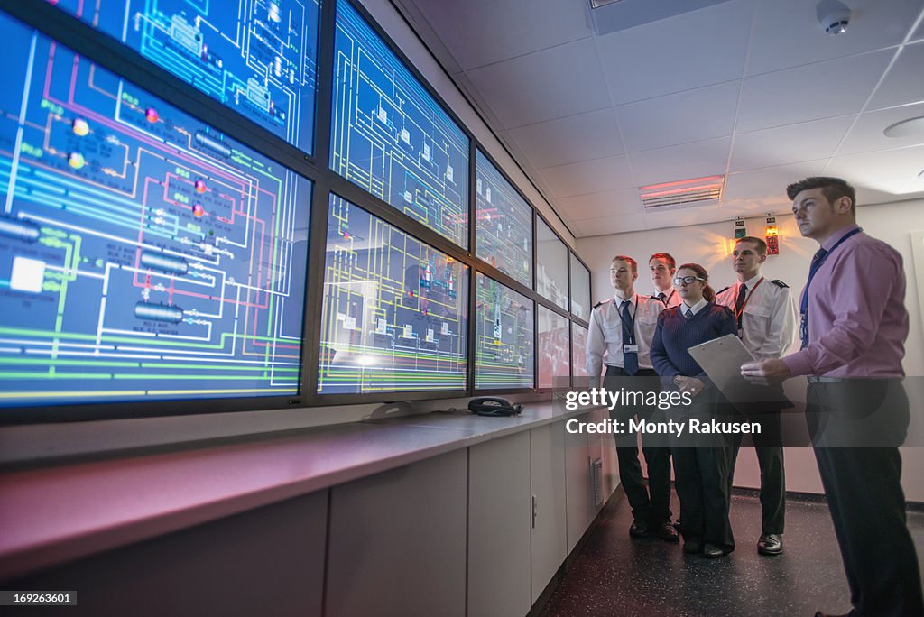 Tutor and students looking at monitors in ship's engine room simulator