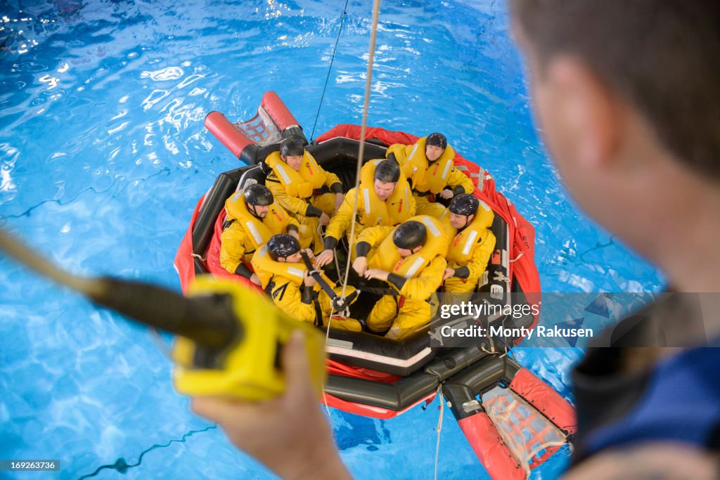 Offshore oil workers hoisted from raft in sea ditching survival training in pool facility