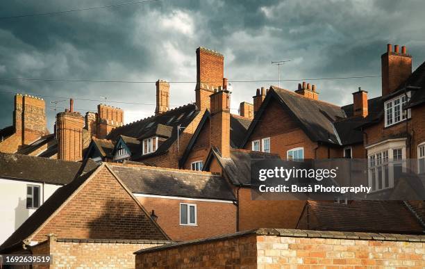 pitched roofs and chimneys of traditional brick houses in england - wohnungsprobleme stock-fotos und bilder