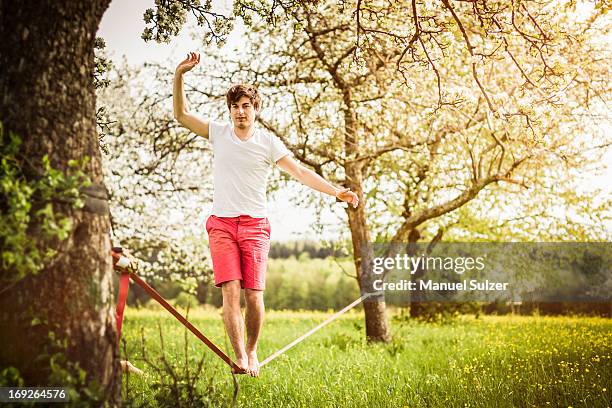 man walking on tightrope in field - slackline foto e immagini stock