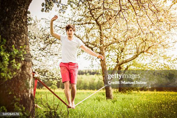 man walking on tightrope in field - tightrope walker stock pictures, royalty-free photos & images