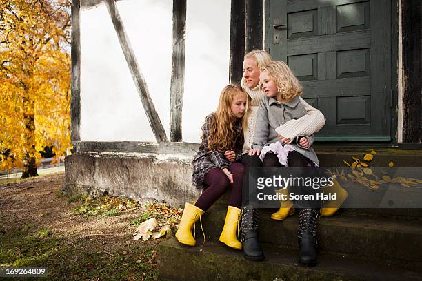 mother and daughters sitting outdoors - autumn sadness stock pictures, royalty-free photos & images